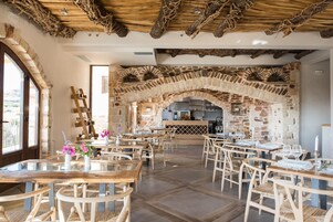 Un restaurante con arcos de piedra, mesas de madera y sillas de mimbre.