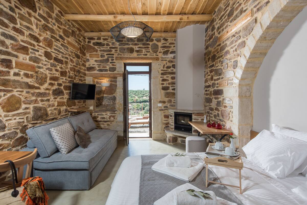 Ein Zimmer mit Stehwänden, einem Sofa, einem Bett, einem Fernseher und einem Kamin.