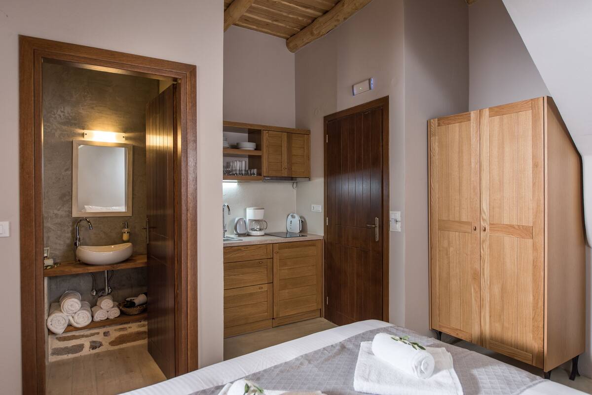Ein Schlafzimmer mit einem Bett, einem Holzschrank, einem Badezimmer mit Waschbecken und Duschbereich.