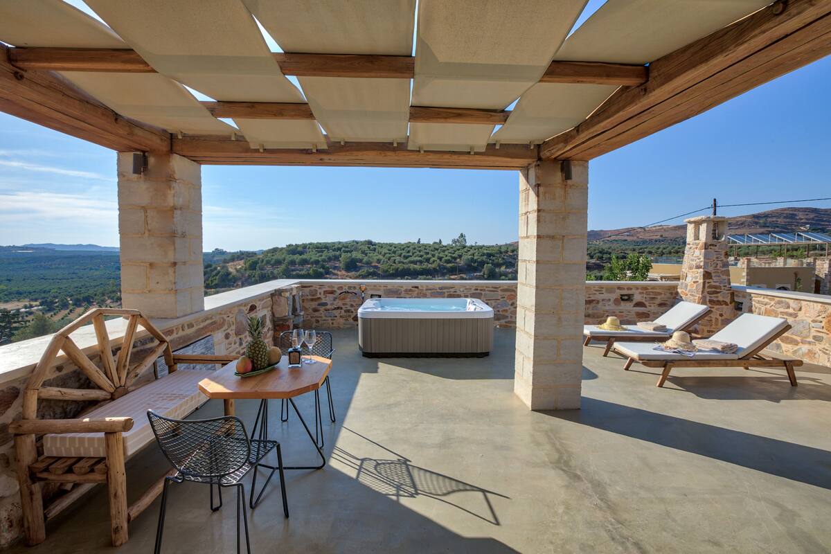 Une terrasse sur le toit équipée d’un jacuzzi, de chaises longues et d’une table en bois avec des chaises.