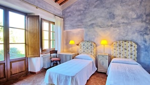 A bedroom with two beds, a chair, a table, and a window. - Sabina (Manciano)