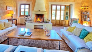 A cozy living room with a fireplace, white sofas, a coffee table, and a bookshelf. - Sabina (Manciano)