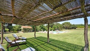 A covered outdoor area with a pool, lounge chairs, and a well-maintained lawn. - Sabina (Manciano)