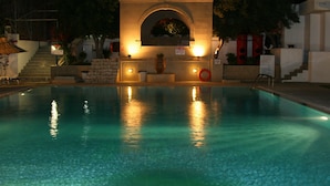 Una piscina con un arco de piedra y escalones que la bordean.