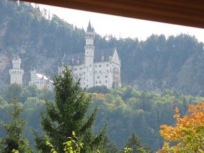 A large castle with multiple towers, surrounded by dense forest and hills. - Alpenhotel Allgäu (Schwangau)