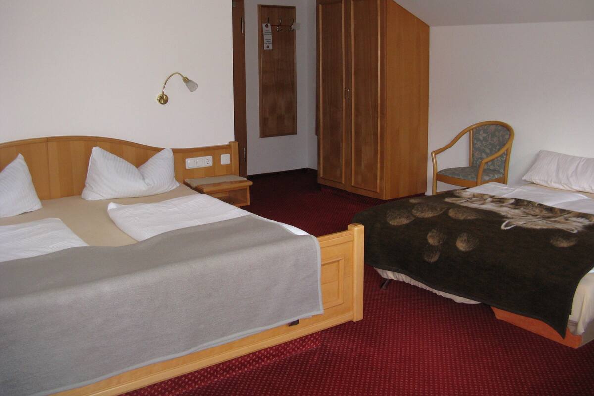 Une chambre d’hôtel avec deux lits, une armoire en bois, une chaise et une table de chevet.
