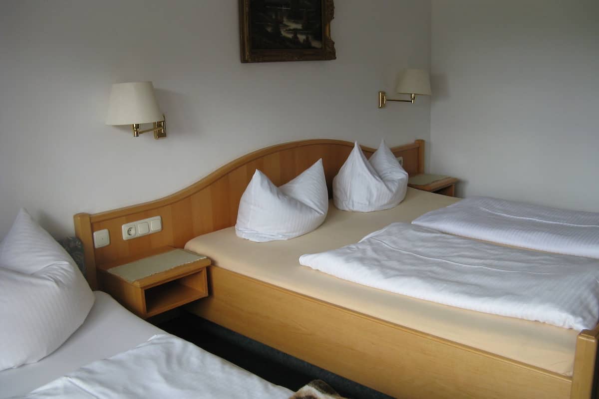 Une chambre d’hôtel avec un lit en bois, deux tables de chevet et deux lampes fixées au mur.