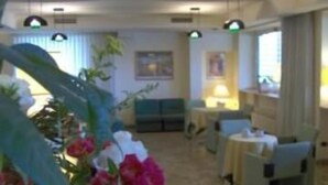 A hotel lobby with a seating area, a reception desk, and a large window. - Hotel Bellariva (Pescara)