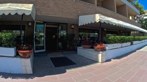 A hotel with a covered entrance, potted plants, and a clear blue sky. - Hotel Bellariva (Pescara)