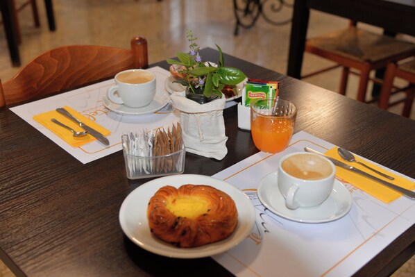 Ein Frühstückstisch mit einem Croissant, Kaffee, Saft und einer kleinen Pflanze.