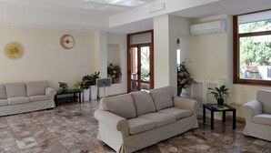 A spacious living room with two beige sofas, a small table, and a potted plant. - Il Romitello  (Rome)