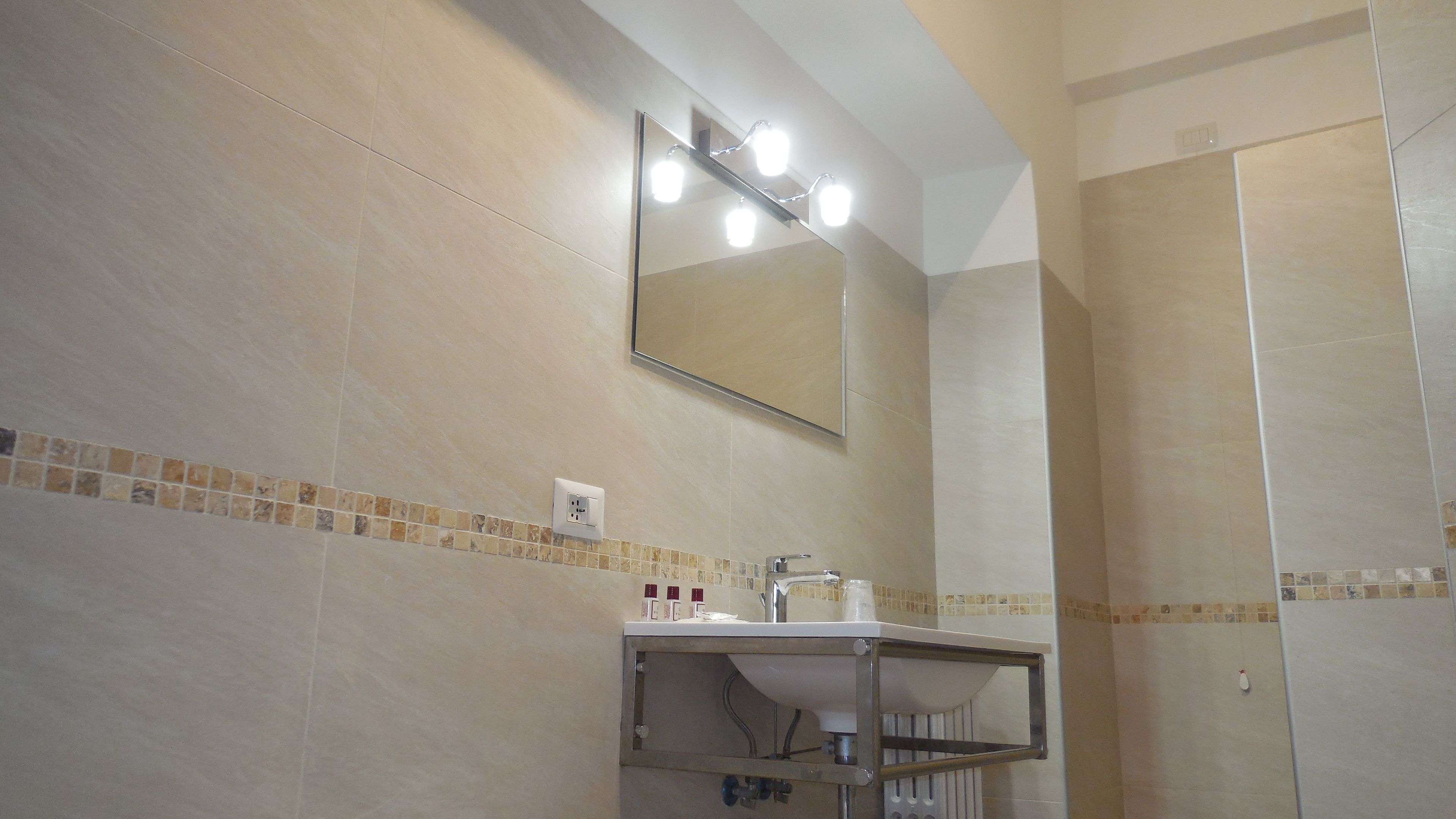 A bathroom with a mirror, vanity, and a shower area.