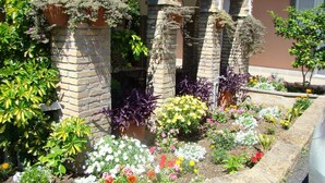 A garden with a variety of flowers and plants, brick arches, and a stone pathway. - Il Romitello  (Rome)