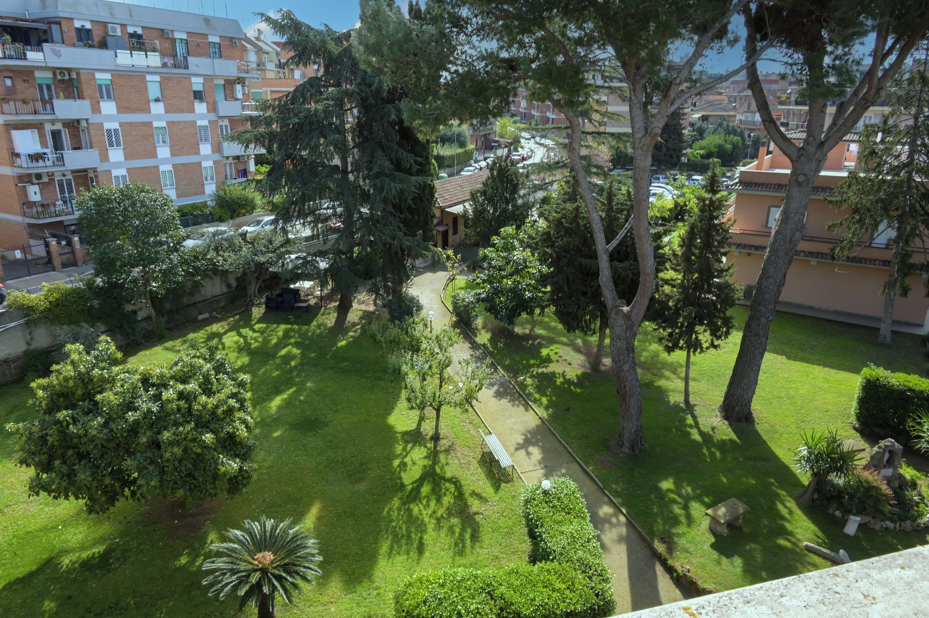 A residential area with a well-maintained lawn, trees, and a pathway.