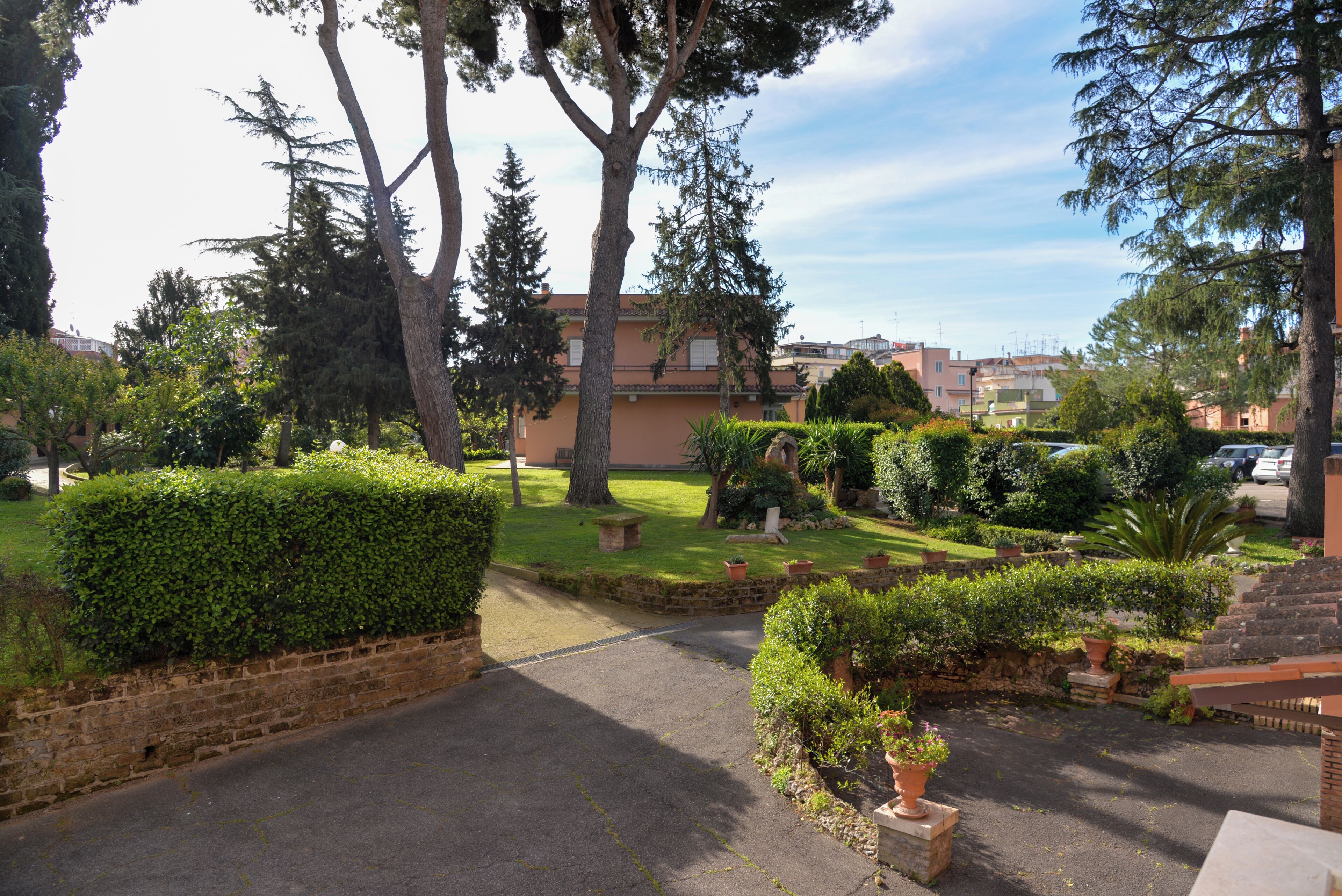 A residential area with a paved driveway, well-maintained lawns, and mature trees.