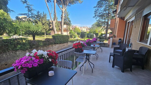 An outdoor patio area with tables and chairs, surrounded by greenery and trees. - Il Romitello  (Rome)