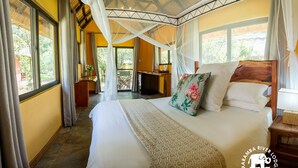 A bedroom with a large bed, a canopy, and a view of the outdoors. - Maramba River Lodge (Livingstone)