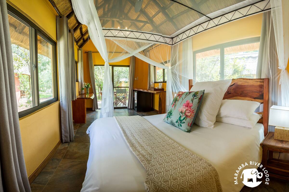 A bedroom with a large bed, a canopy, and a view of the outdoors.