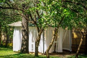A covered outdoor area with a wooden fence, trees, and a white canopy. - Maramba River Lodge (Livingstone)