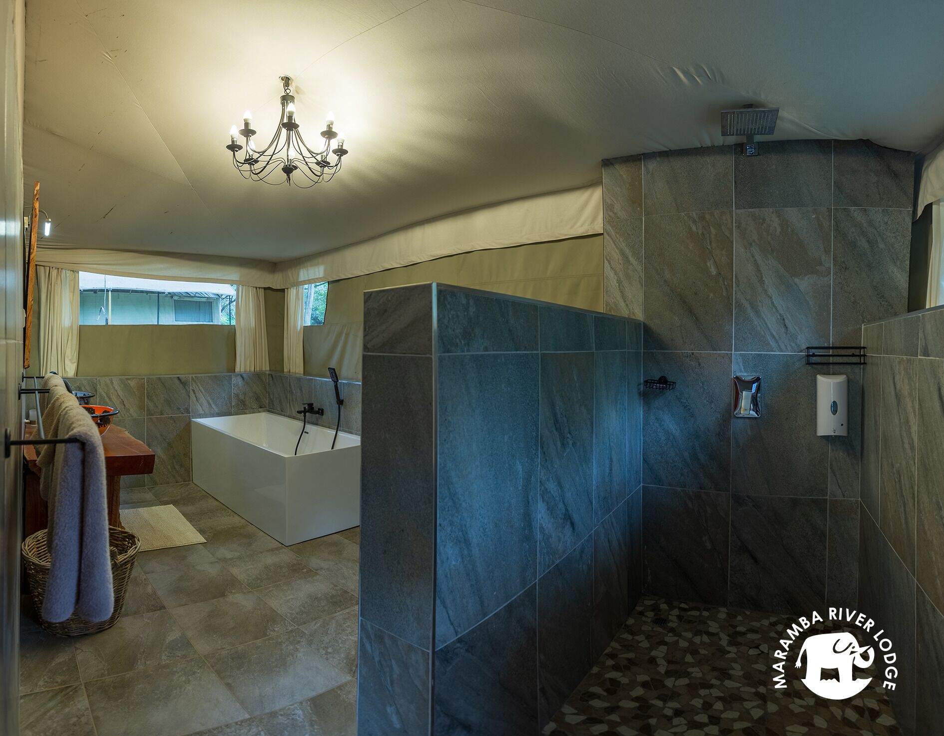 A modern bathroom with a bathtub, shower, and a chandelier.