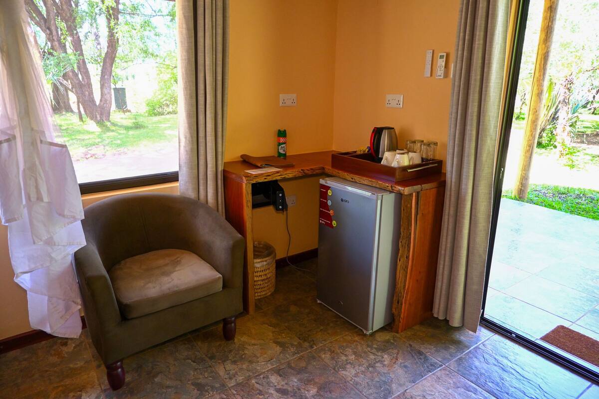 A compact room with a sofa, a small kitchenette, and a view of a garden.