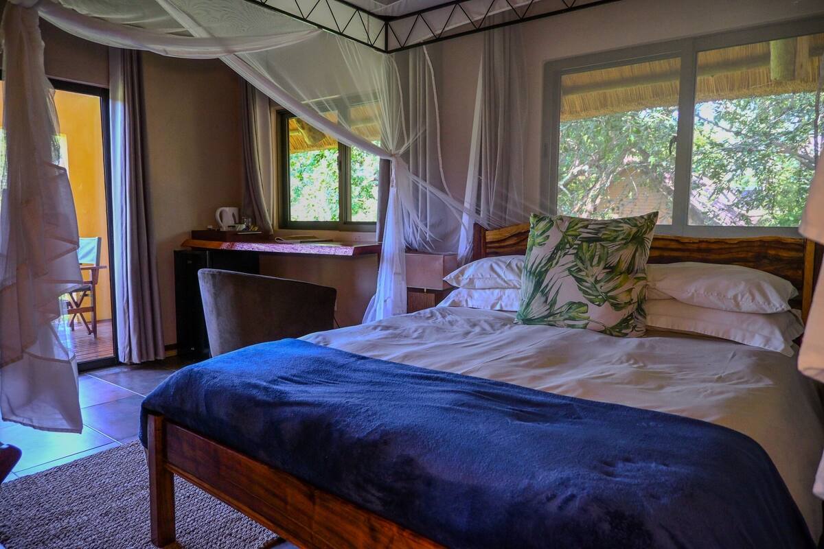 A bedroom with a large bed, a desk, and a chair.