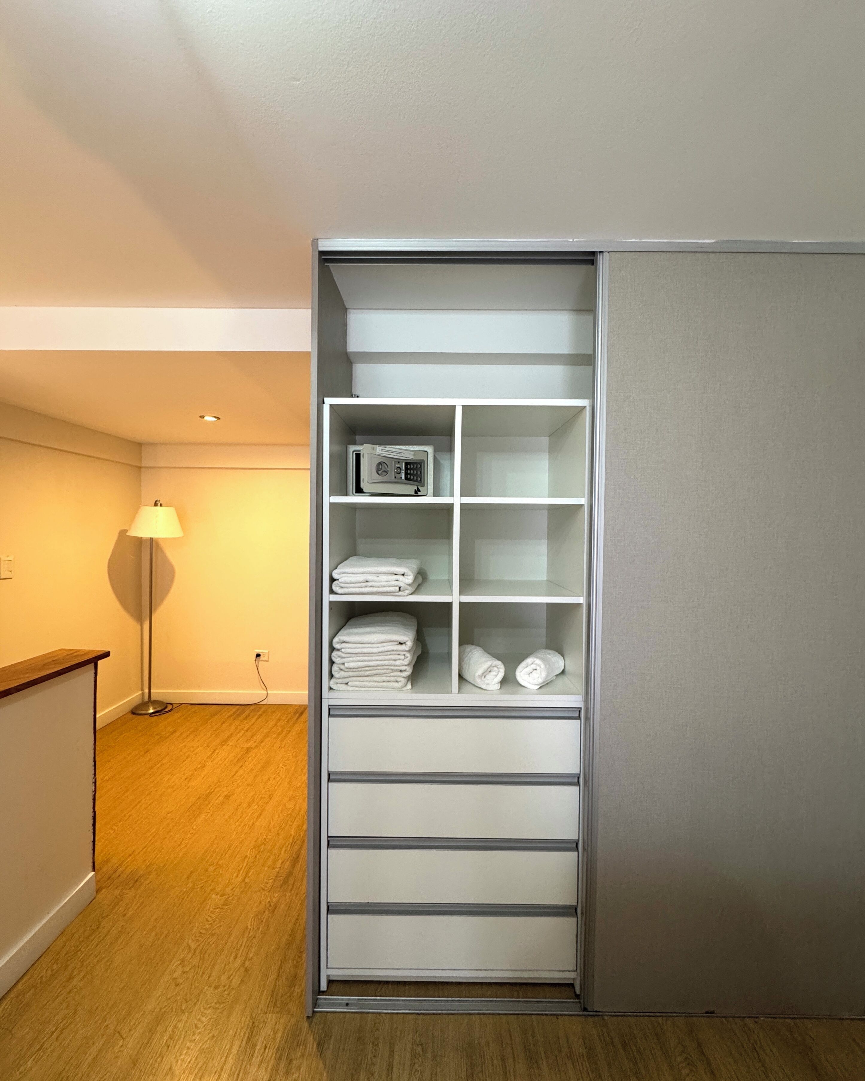 A walk-in closet with shelves and drawers, a lamp, and a microwave.