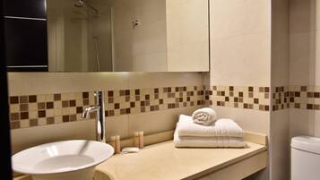 A bathroom with a sink, mirror, towel rack, and shower.