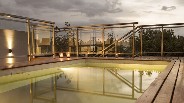 A rooftop pool with glass railings and a wooden deck. - Syrah Suites (Buenos Aires)