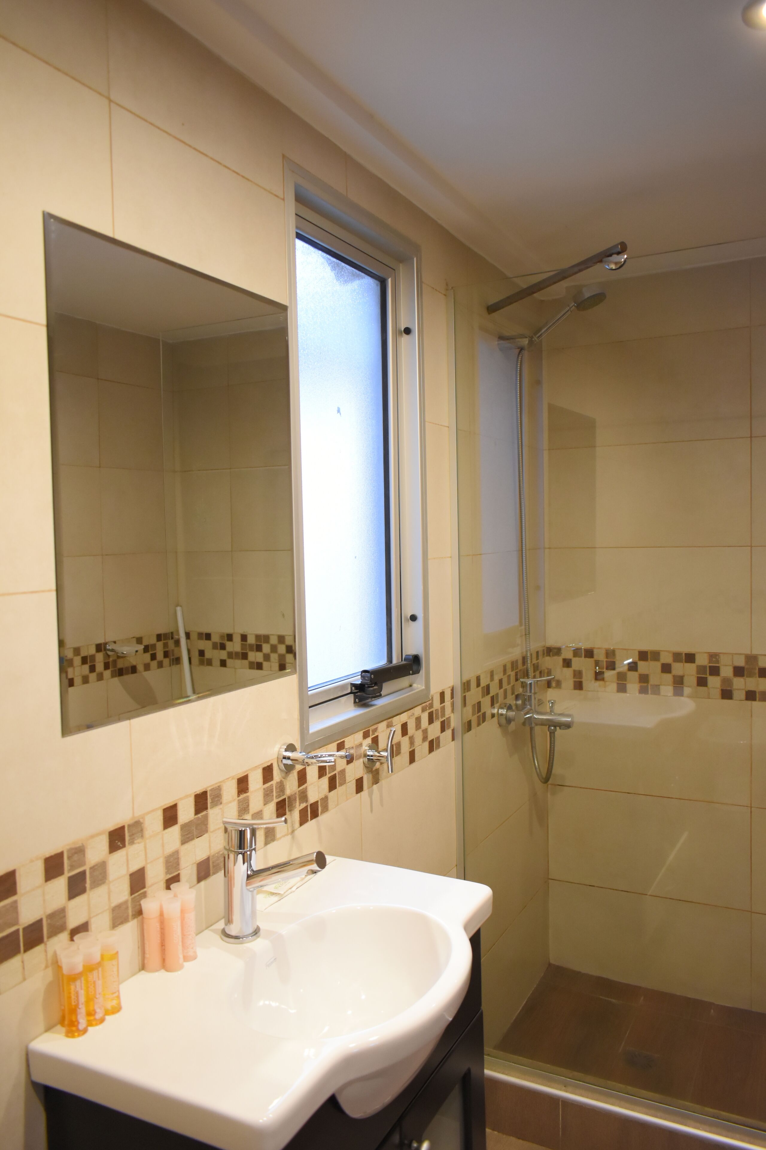 A bathroom with a sink, mirror, and shower.