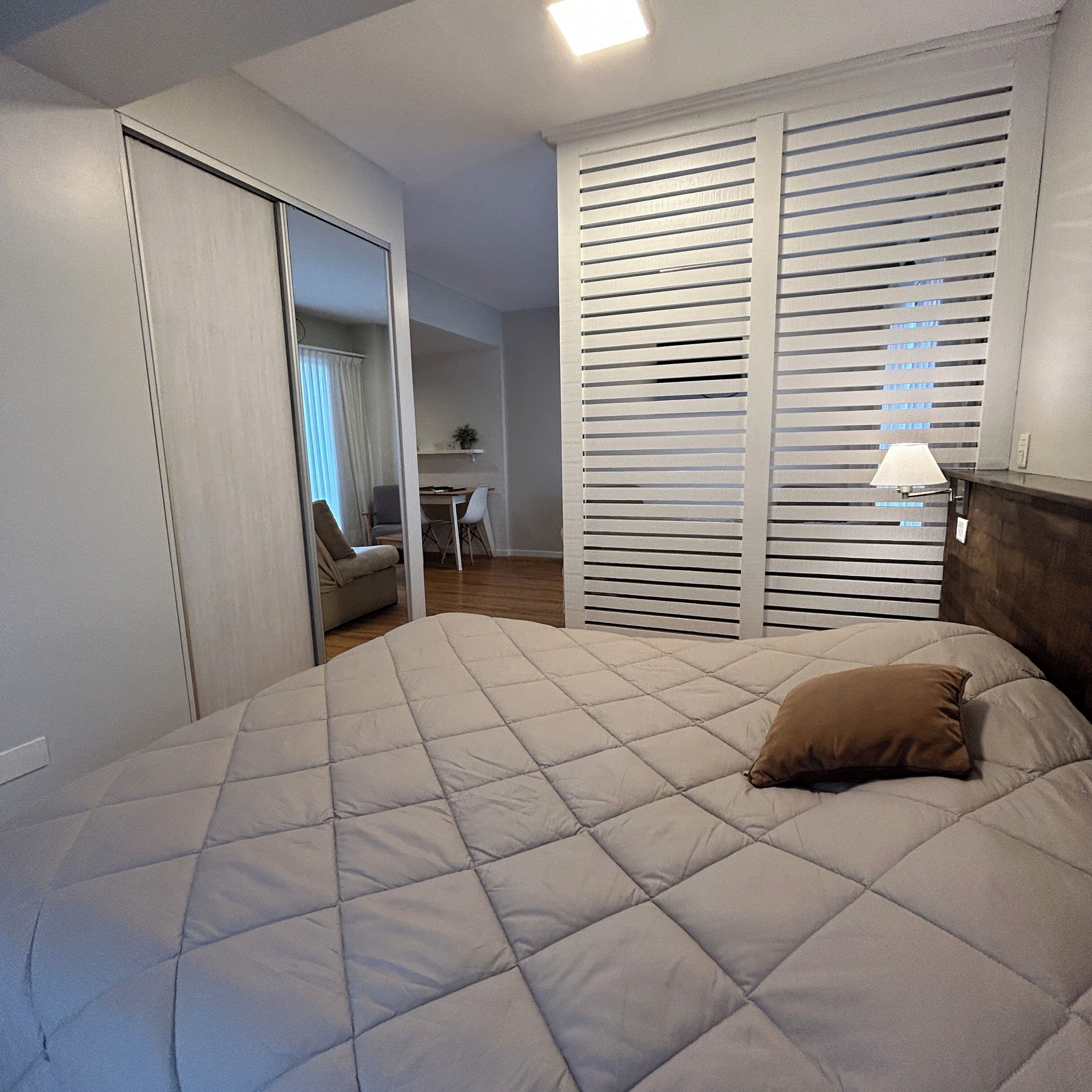 A bedroom with a bed, a wardrobe, and a desk.