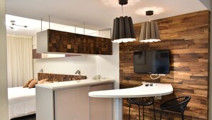 A modern kitchen with a wooden accent wall, a flat-screen TV, and a small dining area with two chairs. - Syrah Suites (Buenos Aires)
