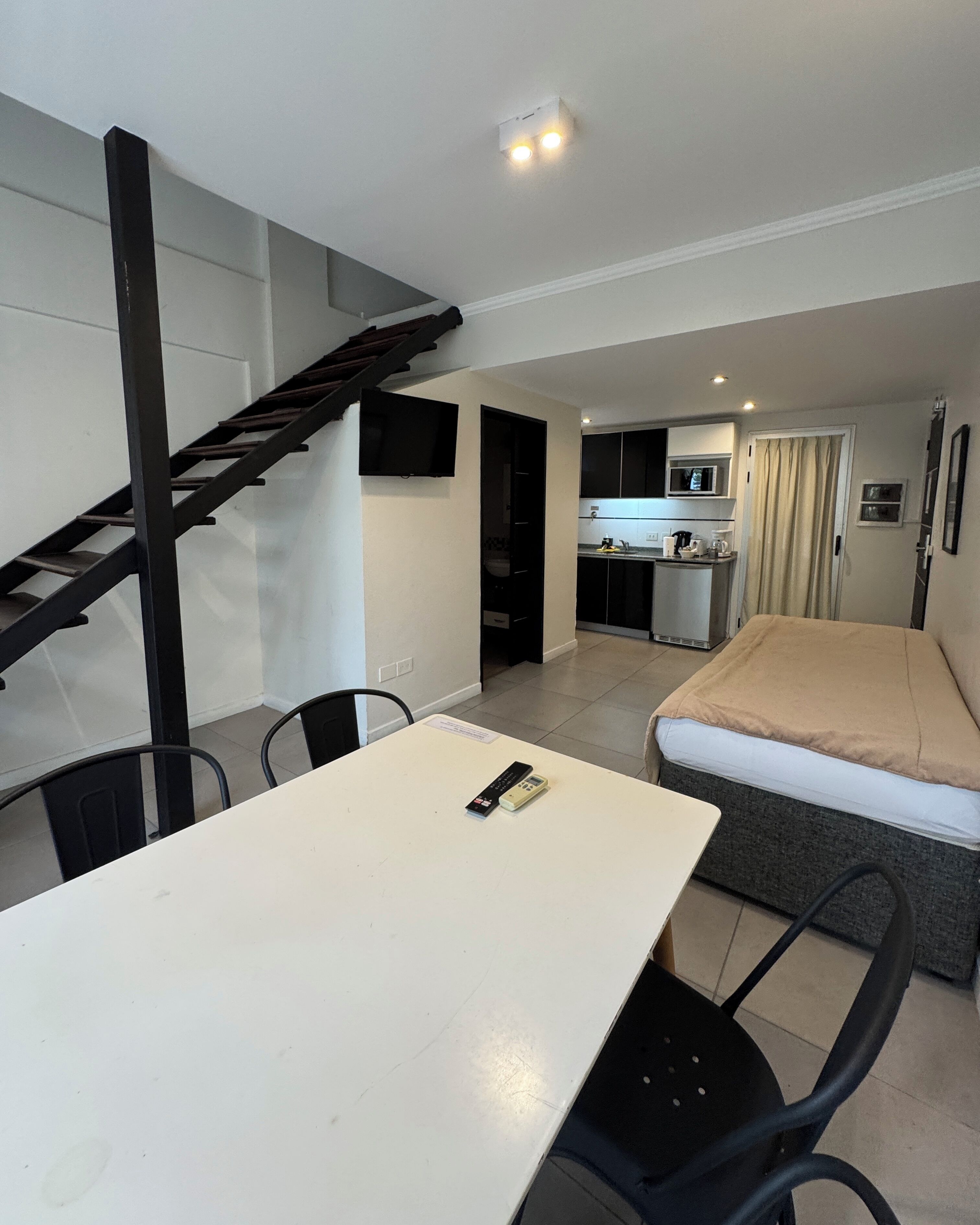 A compact living space with a dining area, kitchenette, and a bed.