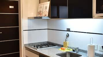 Una cocina moderna con estufa a gas, pileta y lavavajillas. Hay alacenas y una mesada.