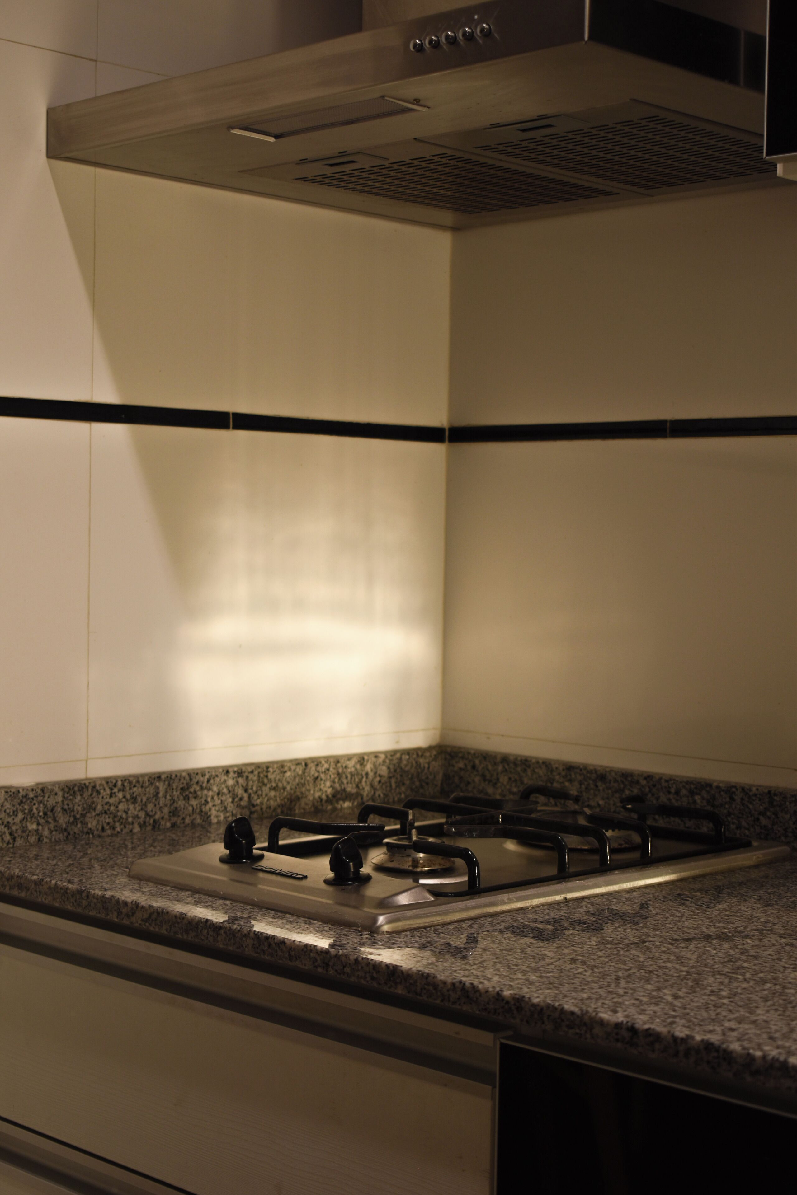 A kitchen with a gas stove, a range hood, and granite countertops.