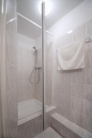 A shower with a glass door, a handheld showerhead, and a towel rack with a towel. - Hotel Felix (Kraków)