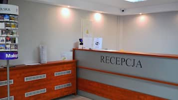 A reception desk with a sign reading 'RECEPCJA' and a 'WiFi' sign above it.