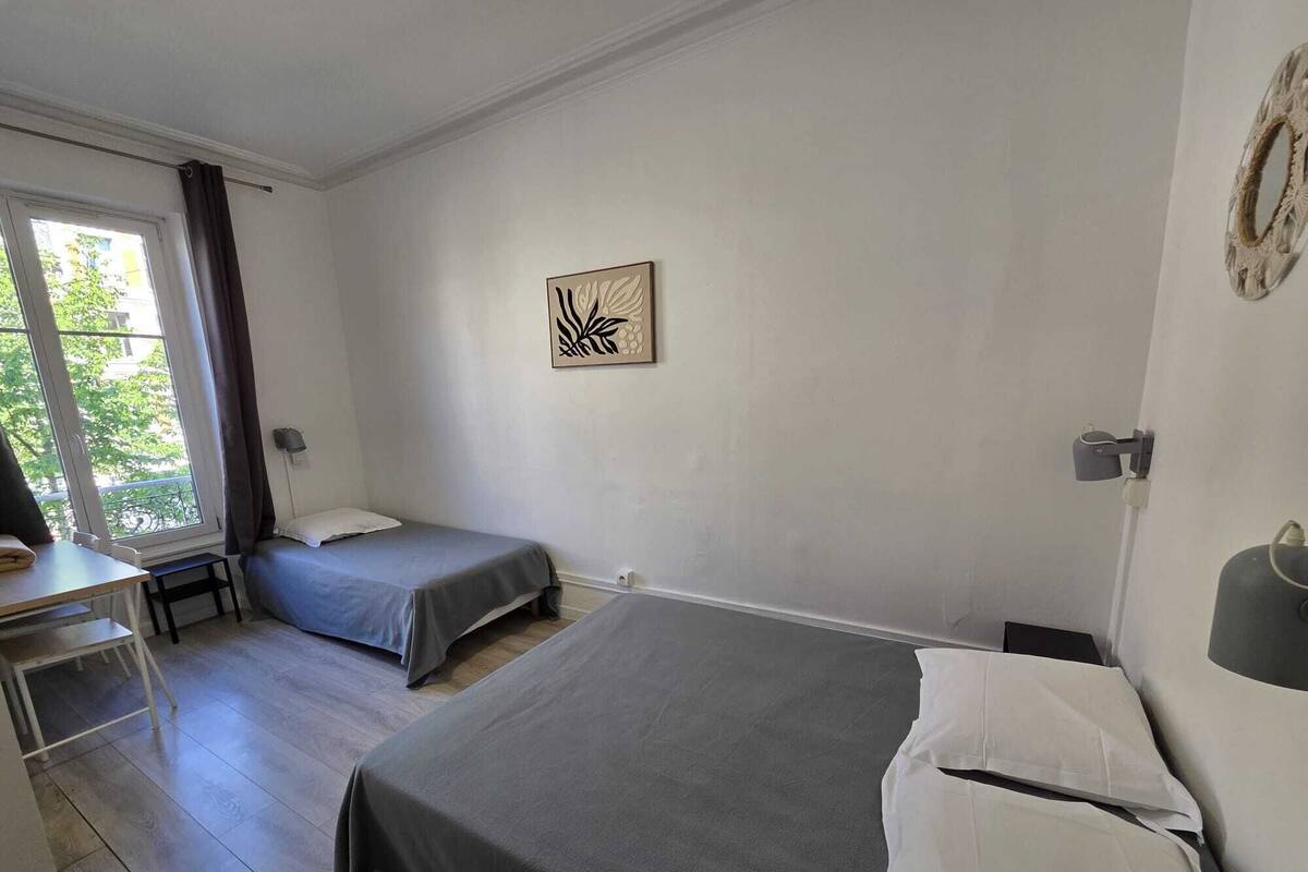 A room with two single beds, a desk, and a chair.