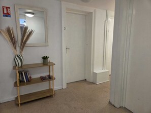 A hallway with a wooden console table, a mirror, and a door with a number. - budget hotel weber-Strasbourg Centre Gare (Strasbourg)