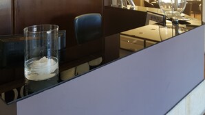 A modern hotel lobby with a reception desk, a seating area with a blue chair, and a large decorative lamp. - Hotel Entredos (Guijuelo)