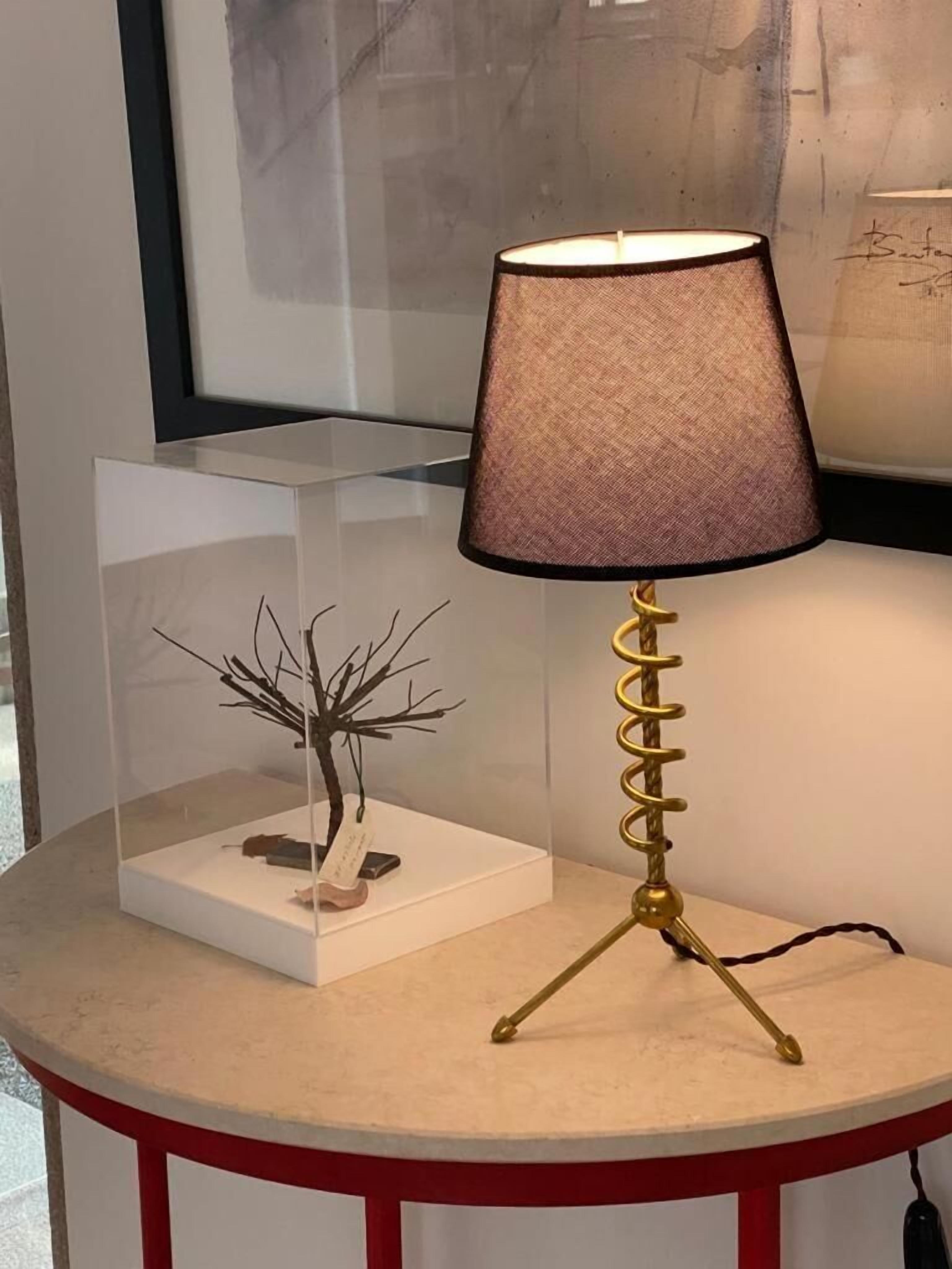 Una mesa con una lámpara, un árbol decorativo y una obra de arte enmarcada.