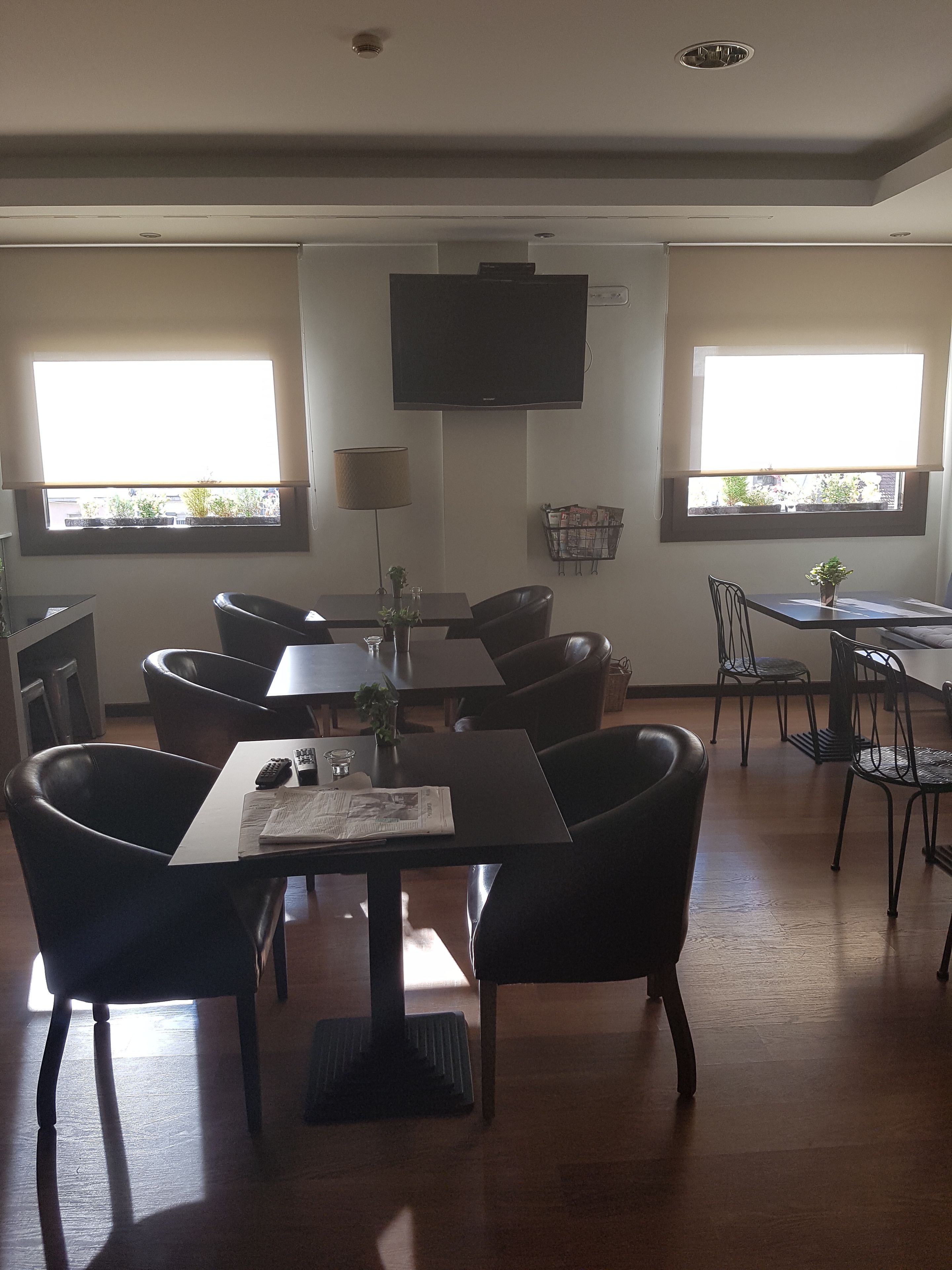 A dining area with a table, chairs, a television, and windows with blinds.
