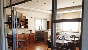 A modern kitchen with a dining area, wooden flooring, and a view through a glass door. - Hotel Entredos (Guijuelo)