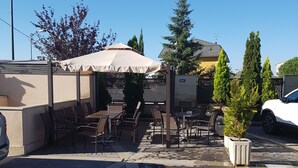 An outdoor patio area with tables and chairs, a covered seating area, and potted plants. - Hotel Entredos (Guijuelo)