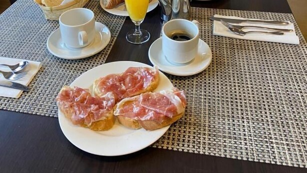 A breakfast table set with croissants, bread, fruit, coffee, and juice. - Hotel Entredos (Guijuelo)
