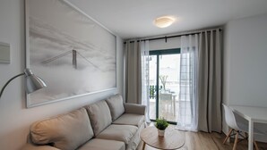A modern living room with a sofa, a table with a plant, a desk, and a view of a bridge through the window. - Los Rosales (Brena Baja)