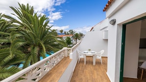 A balcony with a wooden floor, white railing, and a table with chairs. - Los Rosales (Brena Baja)