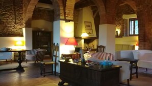 A cozy living room with a fireplace, a dining area with a table and chairs, and a sofa. - Country House Le Case Coloniche (Deruta)