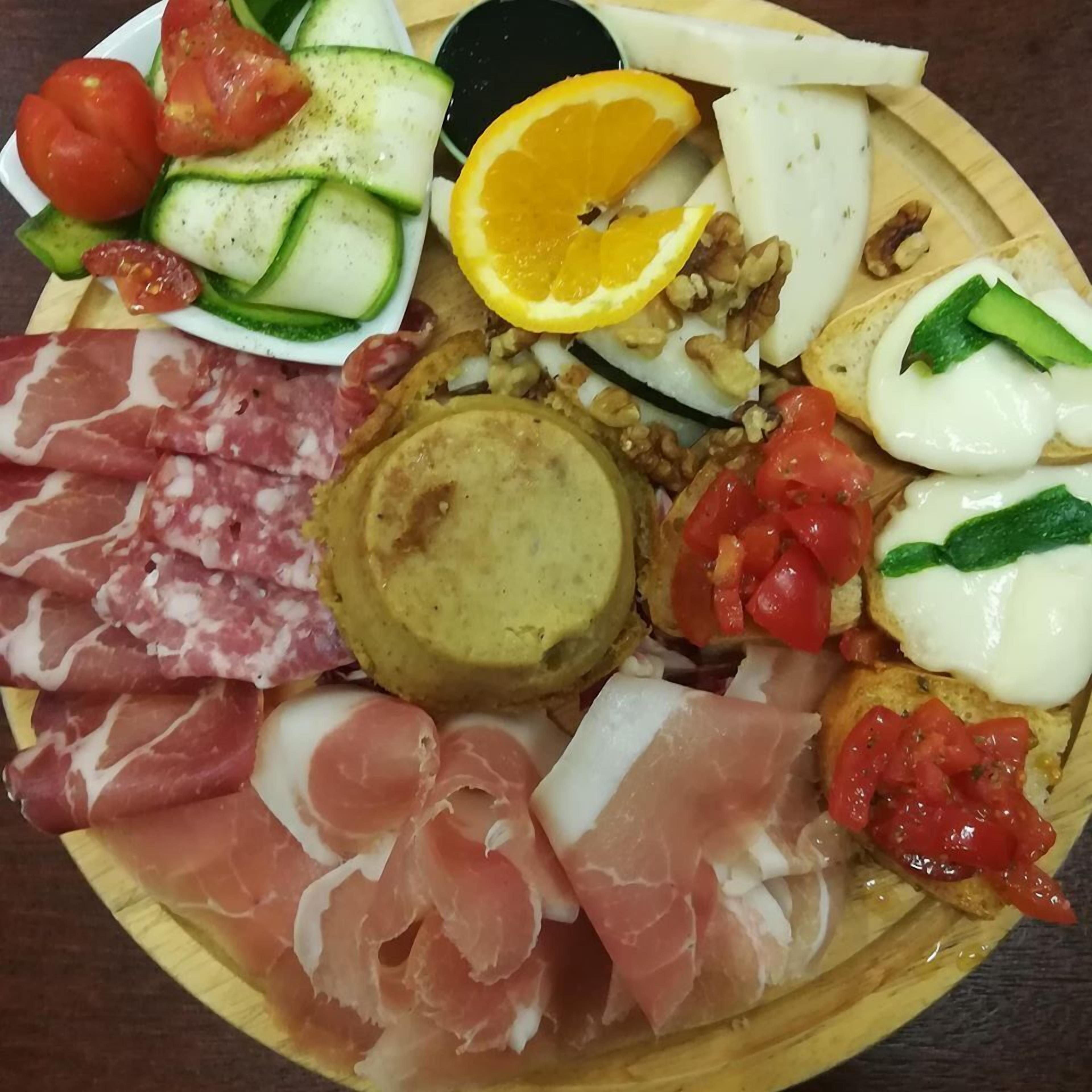 A platter with various meats, cheeses, and vegetables.