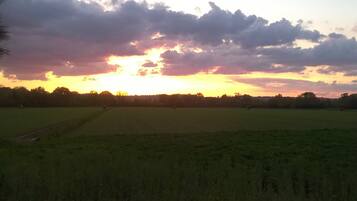 Un ampio campo aperto con un tramonto sullo sfondo.